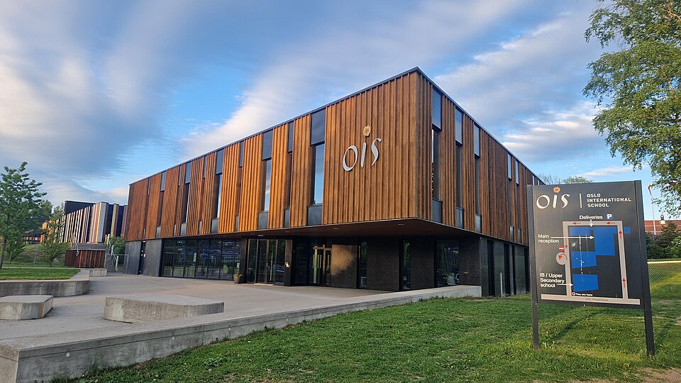 OIS 로고와 Oslo International School 안내판이 있는 노르웨이 베룸 베케스투아의 목재 외벽 교사 건물